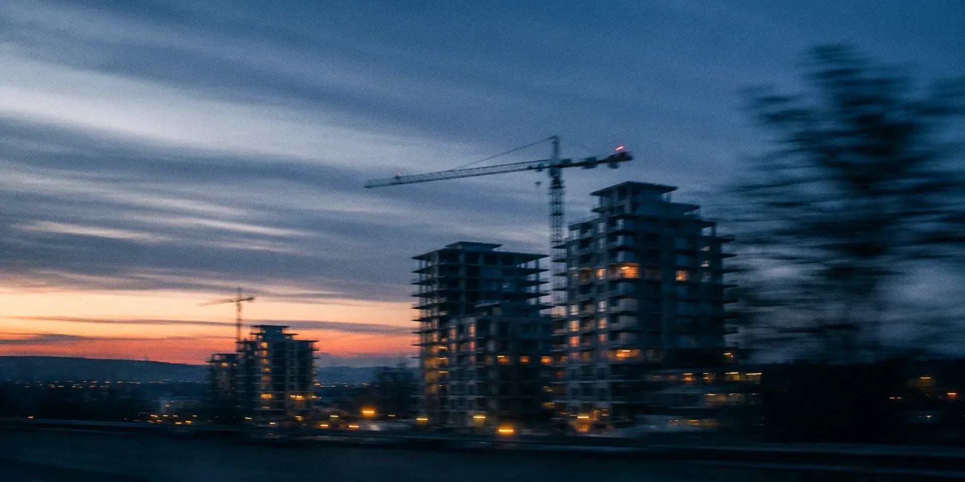 Immeubles résidentiels en construction au crépuscule, avec une grue